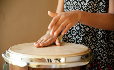 hands of little girl playing the drum in action during day time making music