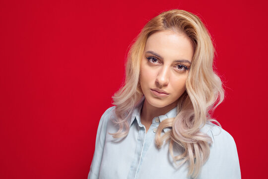 Closeup face of cute blond girl, isolated on red background. Head shot of young beautiful woman
