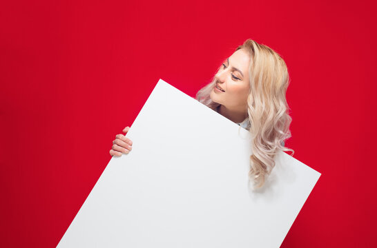 Promoter women holding white board, isolated on red background. Pretty girl showing blank empty paper billboard with blank space for text