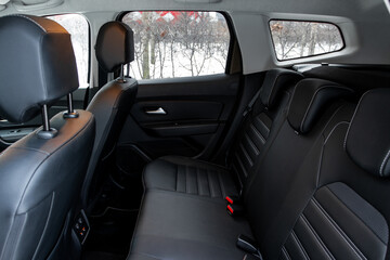 Modern car interior. Clean rear seats with the belts. Three rear seats in the row.  Leather light back passenger seats.
