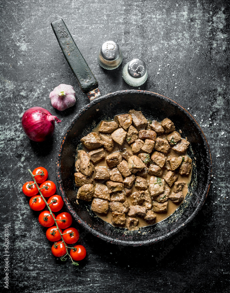 Sticker Pieces of fried liver in a pan with onions, garlic and tomatoes.