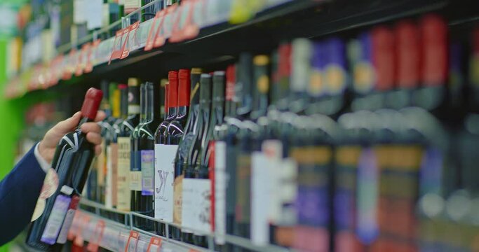 promotion prices in liquor store, closeup of shelf with wine, male hand takes bottle, 4K, Prores