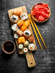 Variants of types of sushi, maki and rolls on a cutting Board with ginger and soy sauce.