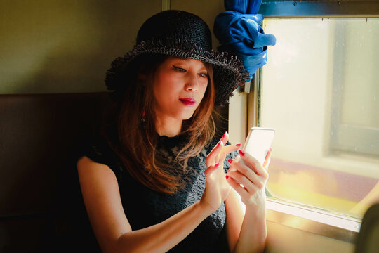 Selective Focus On  Asian Woman Using Smart Phone On Train. Technology And Communication Concept