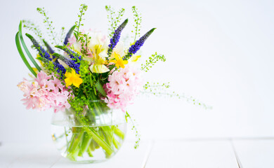 Delicate bouquet in a glass vase on a light background. Image with selective focus