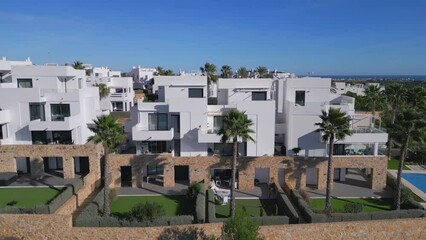 Costa blanca vacation luxury white houses. Bright sunny day. Modern architecture terrace townhouses with pool. Real estate property presentation. Aerial drone side view. 