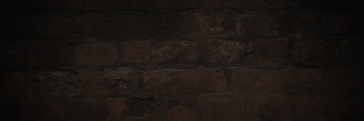 Old brick wall. The texture of weathered grungy brickwork. Panorama of a wall with a rough masonry surface. Dark wide panoramic background for design. Shaded vintage texture with dark vignette.