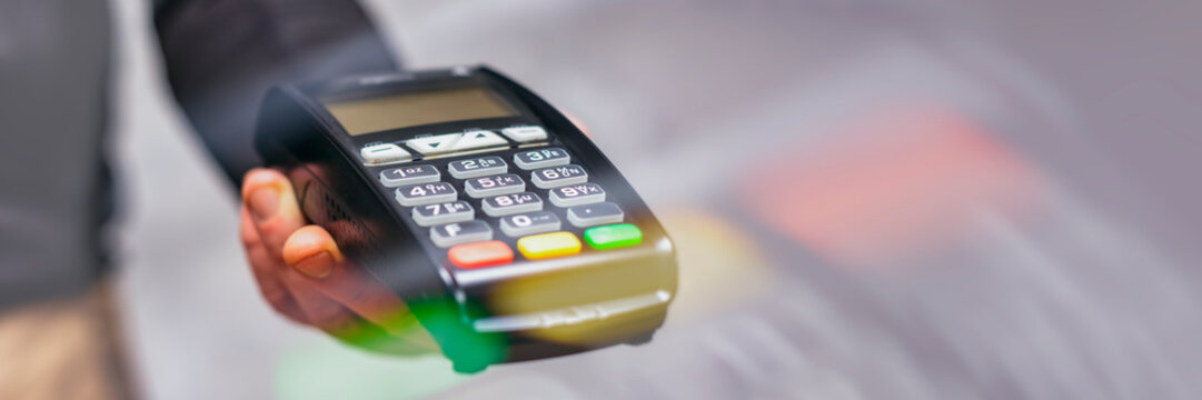 Payment terminal for cashless payments in hand. Paying with a credit card. Long banner.
