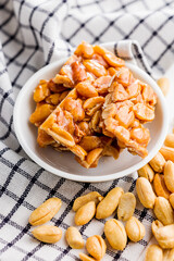 Sweet peanut brittle. Tasty peanuts in caramel on checkered napkin. - obrazy, fototapety, plakaty