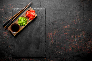 Ginger, wasabi and soy sauce on a wooden stand with chopsticks.