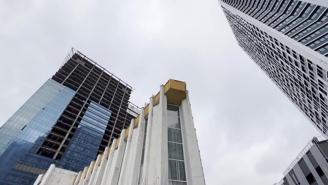 Blending old and new architecture. A city with mixed architecture- sovet union building together whith high modern towers. Low Angle View. tilt up from street to sky.