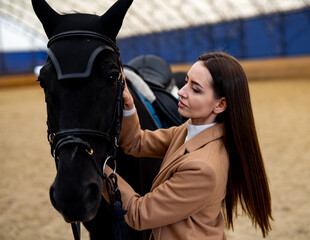 Dark horse with pretty lady jockey. Horse riding training at ranch.