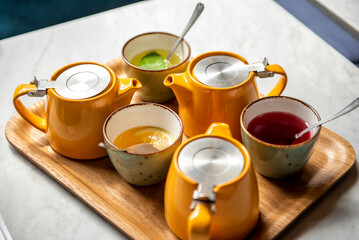 Tree cups of healthy fresh herbal tea with mint and orange on a marble table. 