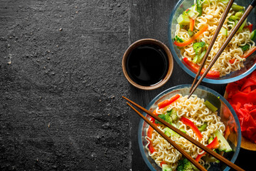 Instant noodles in bowls with vegetables, ginger and soy sauce.