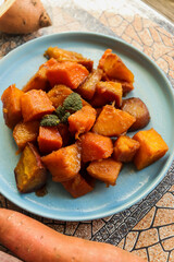 appetizing sliced baked sweet potato in sweet and sour sauce on a blue plate selective focus, delicious sweet potato