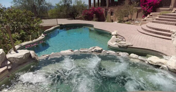 Swimming pool with hot tub and terraced patio at a luxury home in a desert environment.