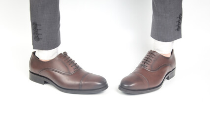 Classic brown leather shoes worn on the hands on a white background