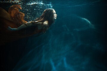 Young beautifull caucasian woman in orange dress under water