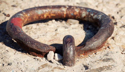 An old rusty cast iron ring used to anchor boats and ships to the concrete of a pier. Extreme closeup detail shot, daylight.
