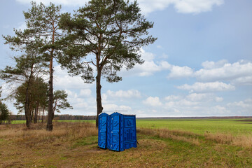 The toilet is blue in the field in summer.