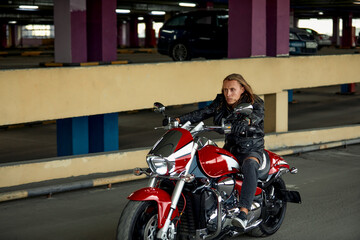 Fototapeta na wymiar Handsome bearded biker with classic style black motorcycle. Cafe racer in garage.