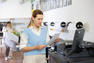 Technician female operator calibrating plotter machine, typing on computer keyboard