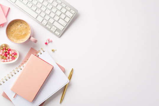 Women's Day concept. Top view photo of keyboard pink notebooks golden pen heart shaped saucer with pushpins and cup of coffee on isolated white background with empty space