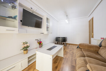 Furnished living room of a house with brown fabric armchairs and an old white bookcase with a TV in the middle
