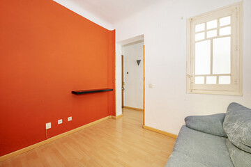 Living room of a house with blue fabric armchairs and an orange wall with a black shelf