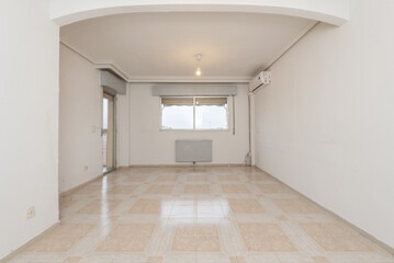 Living room of an empty house with aluminum windows with a radiator below and exit to a terrace with a glass door