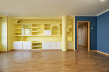 Living room of an empty house with yellow painted plaster work furniture and another blue wall and plaster molding on the ceiling