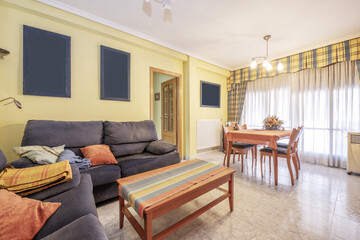 Living room of a house with blue fabric armchairs and cherry wood coffee and dining table
