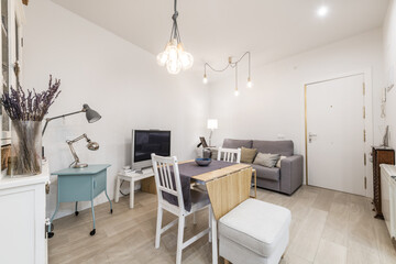 Living room of a house with gray fabric armchairs with a folding wooden table in the center and a white access door