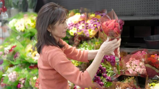 Attractive woman with dimples looking at flower bouquets at florists shop