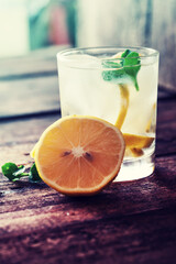 Glasses of water with lemon over rustic wooden background