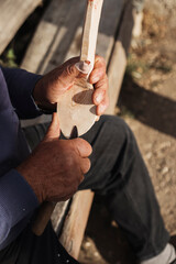 Hands carving spoon from wood, working with chisel close up. Process of making wooden spoon. Wooden workshop.