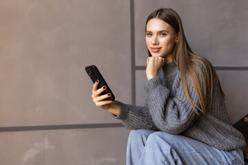 Shot of an attractive young woman sitting on the stairs and using her cellphone while home