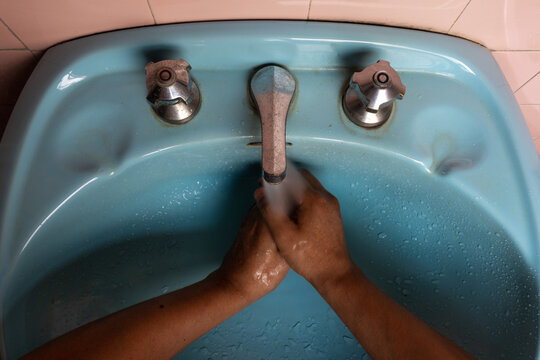 Latino lavándose las manos en pileta celeste