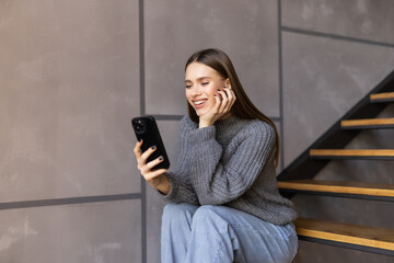 Shot of an attractive young woman sitting on the stairs and using her cellphone while home