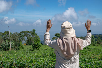 The girl standing on the green tea garden when spring season with the blue sky. The photo is suitable to use for traveler content media, holiday background and garden poster.