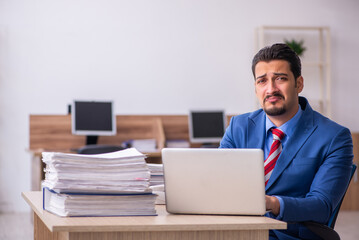 Young male employee unhappy with excessive work at workplace