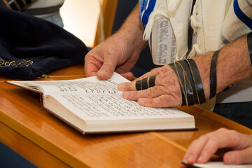 REHOVOT, ISRAEL - JANUARY 19, 2018: An adult man pointing at a phrase in a bible book (sefer torah), while reading a pray