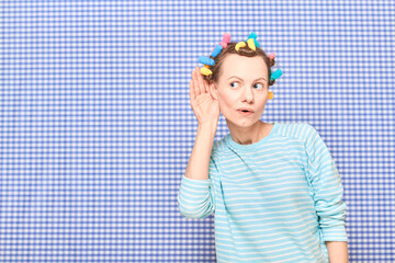 Surprised young woman with colorful hair curlers on head