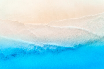 Obraz na płótnie Canvas Aerial view of clear blue sea with waves and empty white sandy beach at sunset. Summer in Zanzibar, Africa. Tropical landscape with white sand and azure water. Ocean. Top view. Nature background