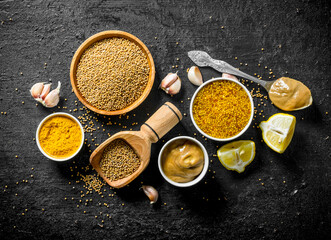 Assortment of different types of mustard with lemon pieces and garlic.