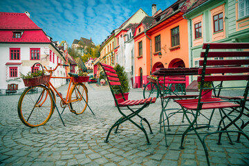 Decorative bicycle next to cafe bar with Stone paved old street and colorful buildings in city...