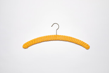 Recycled yellow hanger covered with crochet work. Crocheted shell stitch cloth hanger cover. Slow fashion, circular economy, retro style, renew DIY household, wardrobe decoration.