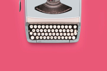Overhead top view of a vintage aqua blue typewriter against a pink background