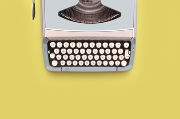 Overhead top view of a vintage aqua blue typewriter against a yellow background