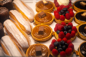 Assortment of french fresh baked sweet pastry with fresh fruits and berries in confectionery shop